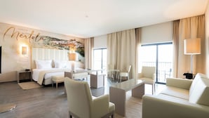 A modern hotel room with a bed, a sitting area with a glass table, and a mural on the wall. - Vila Gale Collection Hotel Monte do Vilar (Beja)