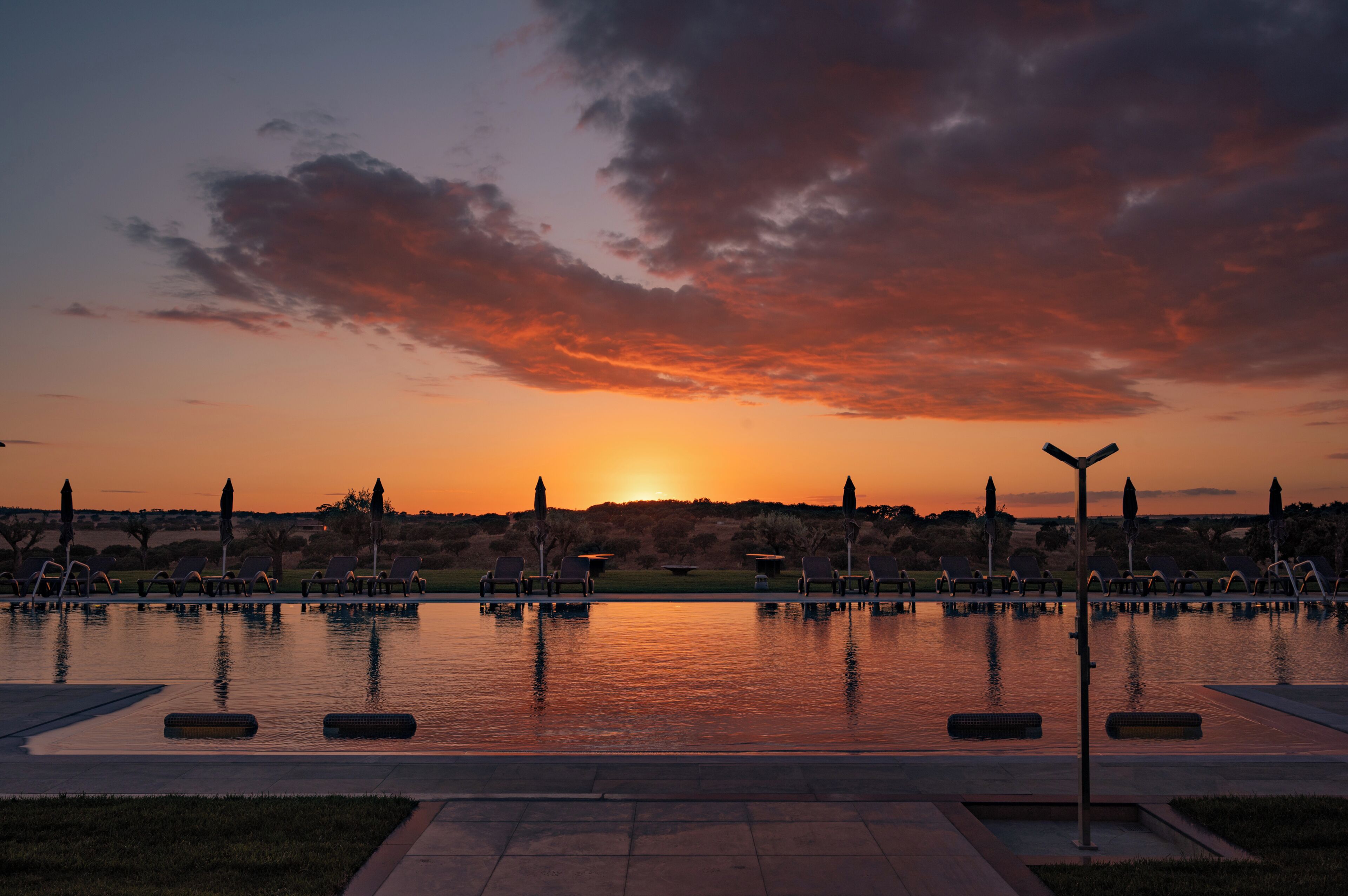 Un capvespre sobre una piscina tranquil·la amb gandules i un cel serè.