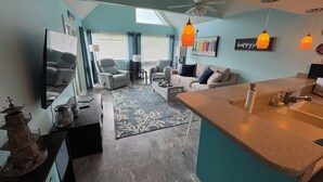Een moderne woonkamer met een bank, fauteuils, een salontafel en een eethoek met een keukentoog.