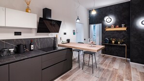 Moderni keittiö, jossa on tumma työtaso, puinen ruokapöytä ja mustat tuolit.