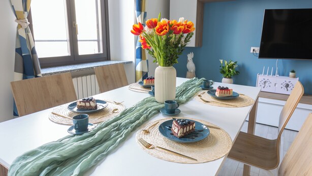 A dining table set with placemats, plates, and a vase of flowers. - OurJoy Condo, 55sm, free private parking and breakfast, high-speed WIFi and A/C (Milano)