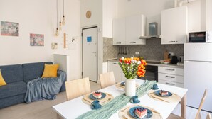 A modern kitchen with white cabinets, a microwave, and a sink. There is a dining table with plates and a vase of flowers. - OurJoy Condo, 55sm, free private parking and breakfast, high-speed WIFi and A/C (Milano)
