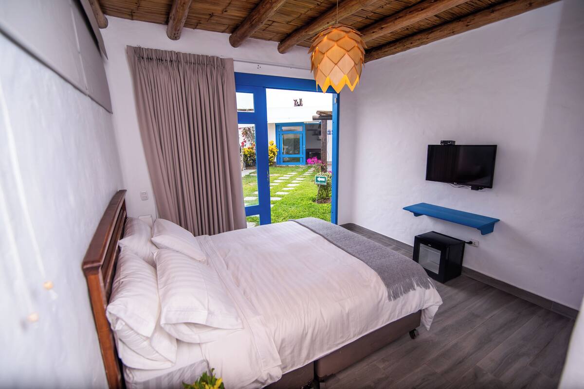 A bedroom with a bed, a TV mounted on the wall, and a small desk.