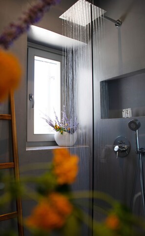 Ein Badezimmer mit Dusche, Fenster und einer Blumenvase.