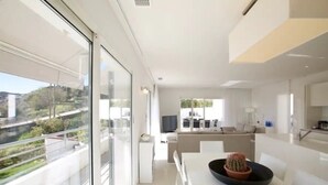 Ein modernes Interieur mit Essbereich, Küche und einem großen Panoramafenster mit Blick auf Grünflächen.