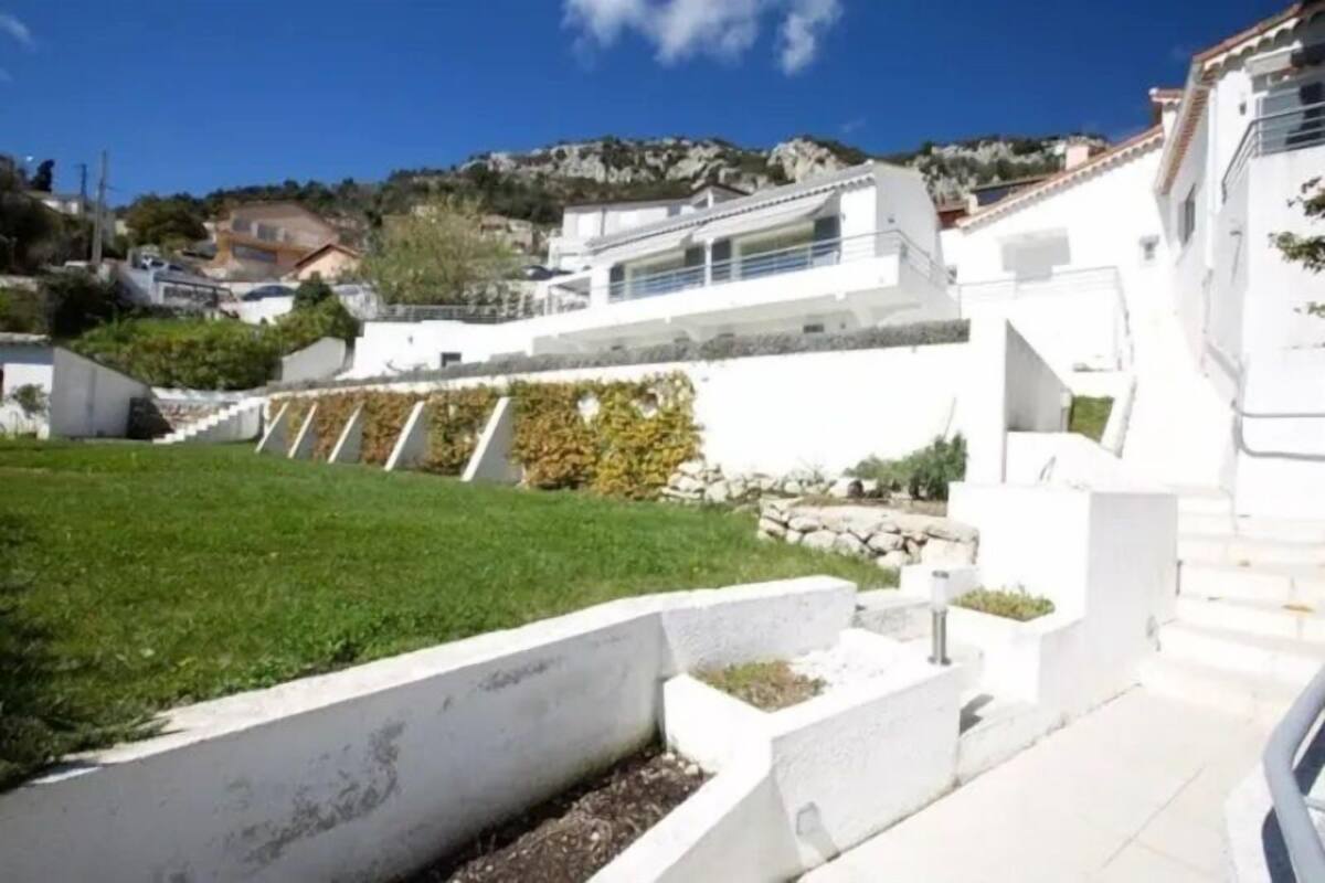 Zona residencial con edificios blancos, césped y una colina al fondo.
