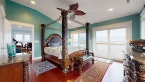 A spacious bedroom with a four-poster bed, a large window, and a view of the ocean. - OCEAN VIBES ON THE INTRACOASTAL (Wilmington)