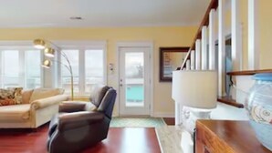 A living room with a sofa, armchair, and a lamp. There is a door leading to a balcony. - OCEAN VIBES ON THE INTRACOASTAL (Wilmington)