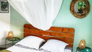 Un dormitorio con una cama, dos mesitas de noche, un tocador, un espejo y una lámpara de pared.