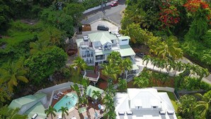 Un resort de varios pisos con zona de piscina, múltiples balcones y exuberante vegetación tropical.