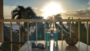 Un balcón con una mesa, dos vasos de líquido azul y un cuenco decorativo.