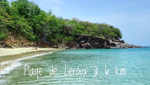 Una playa con agua turquesa cristalina y un acantilado rocoso al fondo.