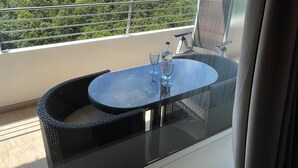 Un balcón con mesa y sillas de vidrio, con vistas a un paisaje verde.