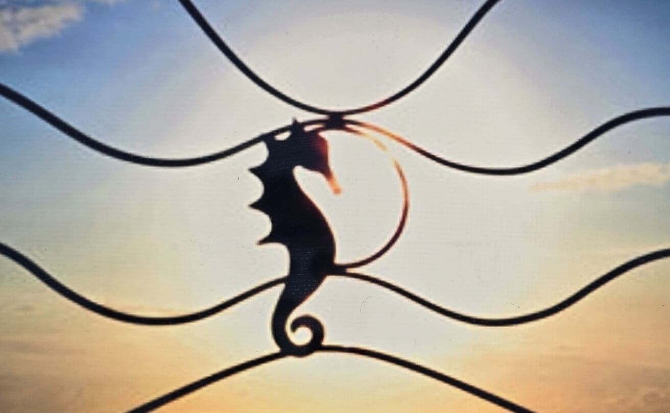 La silhouette d’une tête de cheval, agrémentée d’un élément décoratif, peut-être un logo ou un emblème, se détache sur un fond de ciel.