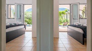 A hotel room with two beds, a view of the pool, and a patio area with chairs. - Kournas-sleeps8-parking-garden-pool-petfriendly (Apokoronas)