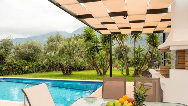 A poolside area with a table, chairs, and a fruit bowl. - Kournas-sleeps8-parking-garden-pool-petfriendly (Apokoronas)