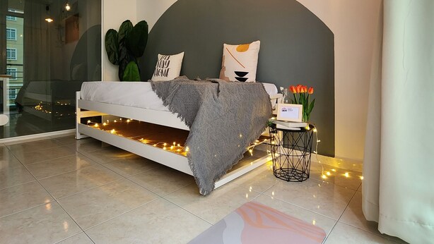 A modern bedroom with a bed, bedside table, and a view of the outside. - Ixora Coliving Lifestyle Homestay (Malacca City)