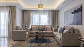 A modern living room with a beige sofa set, a coffee table, and a large abstract painting on the wall.