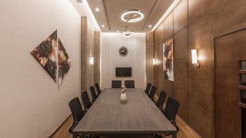 Una sala de conferències amb una taula llarga, cadires, un rellotge i obres d'art a les parets.