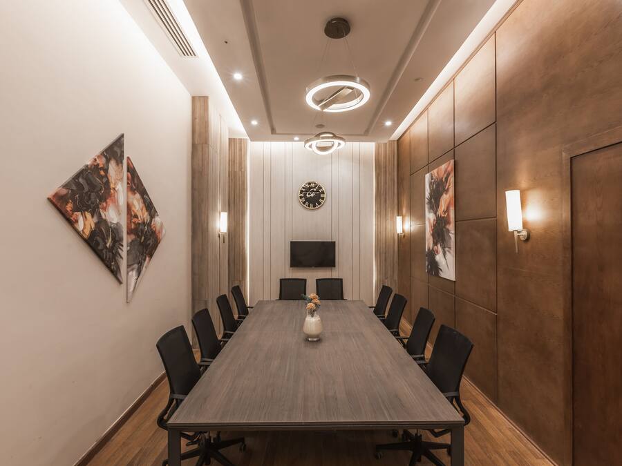 Una sala de conferències amb una taula llarga, cadires, un rellotge i obres d'art a les parets.