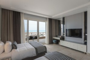 A modern hotel room with two beds, a large TV, and a balcony with a view of the city.