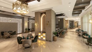 A spacious lobby with a central bar area, seating arrangements, and decorative lighting fixtures. - Gewan Resort New Alamein (Marsa Matrouh)