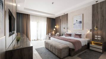 A modern hotel room with a large bed, a desk, and a seating area.