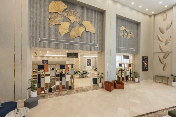 A spacious lobby with a seating area, a reception desk, and decorative wall art. - Gewan Aqua Park Resort - New Alamein (El Alamein)