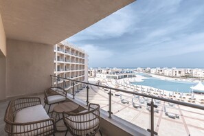 A balcony with wicker furniture overlooking a pool and a cityscape.