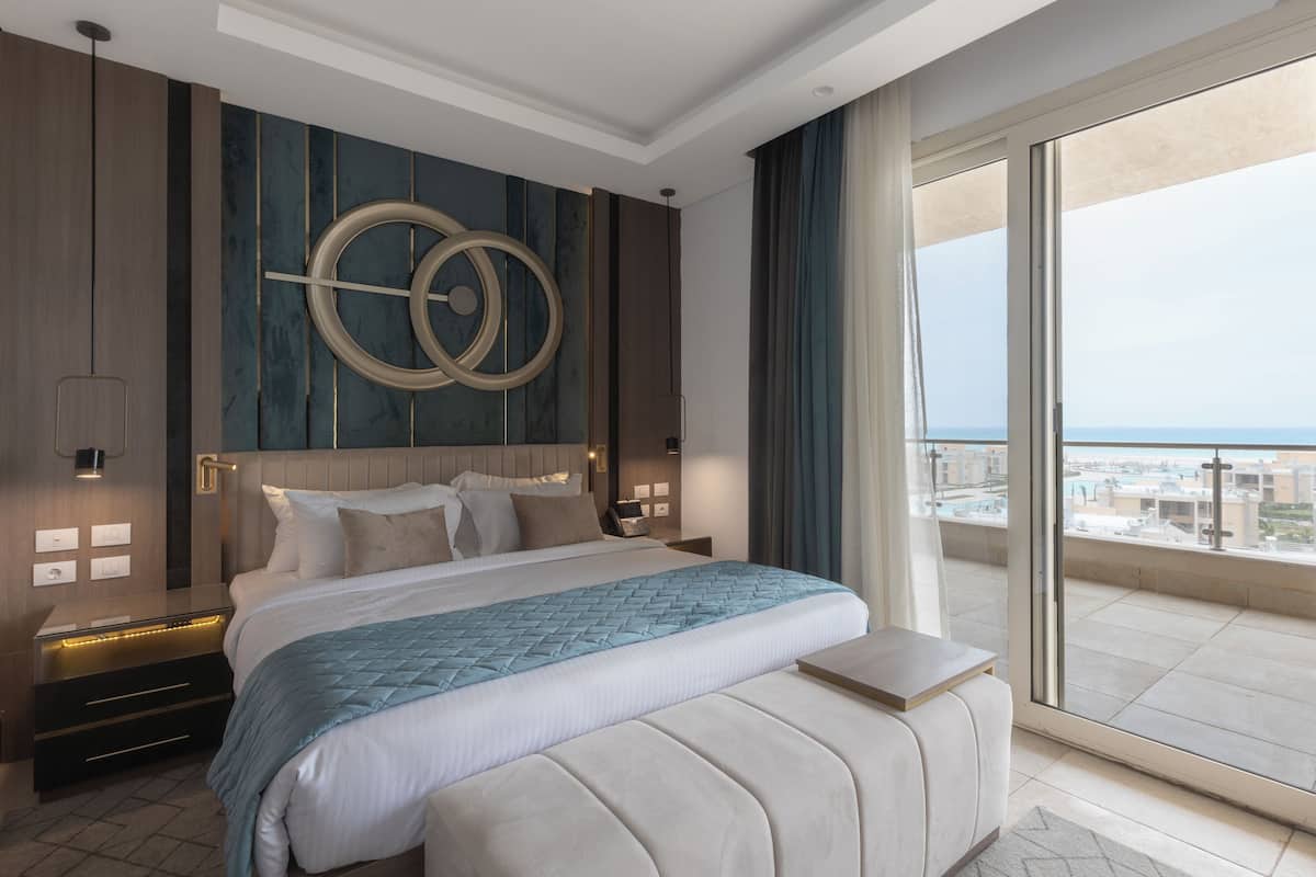 A modern hotel room with a large bed, a view of the city, and a balcony.