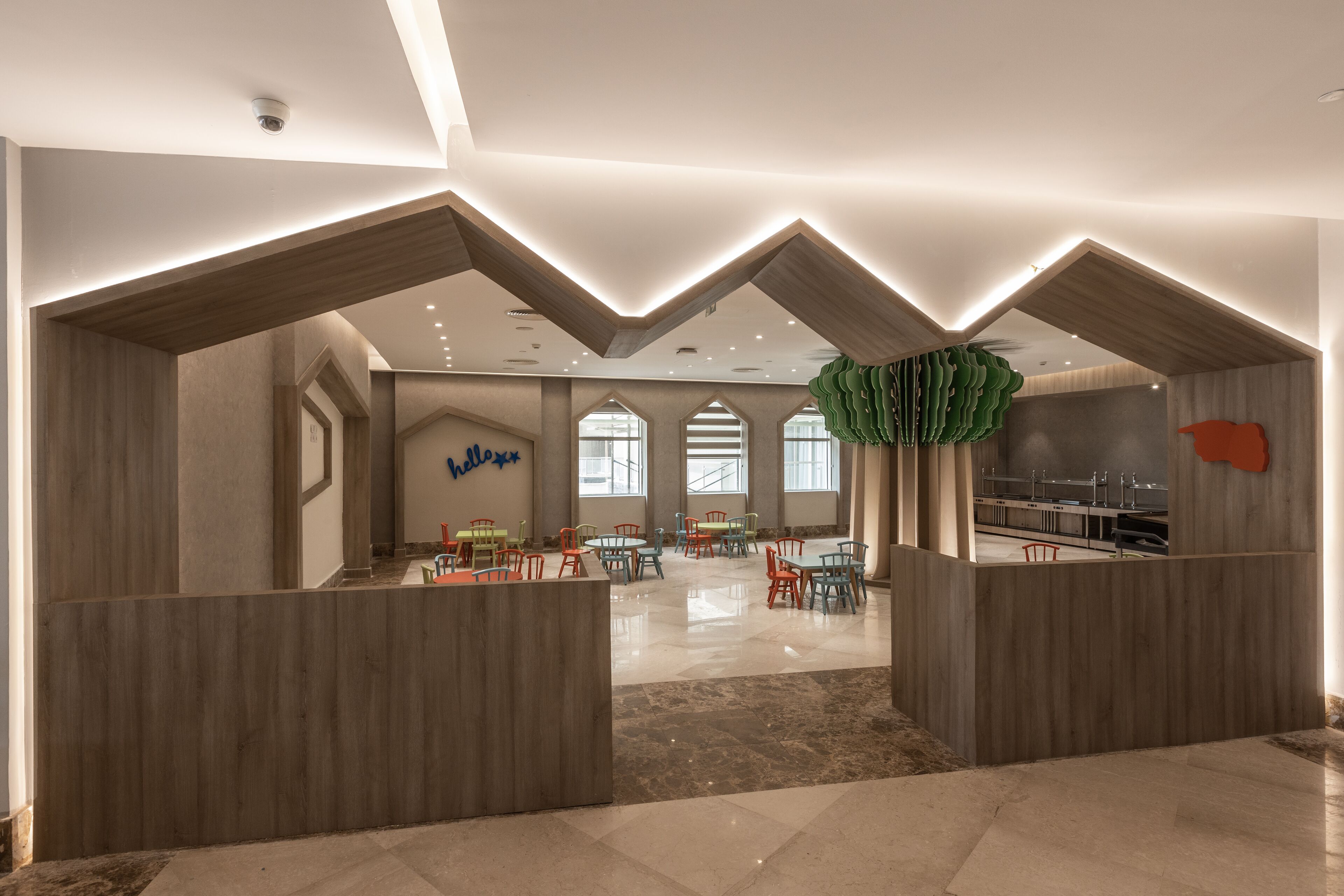 A spacious lobby with a modern design, featuring a central seating area with colorful chairs and a wooden reception desk.