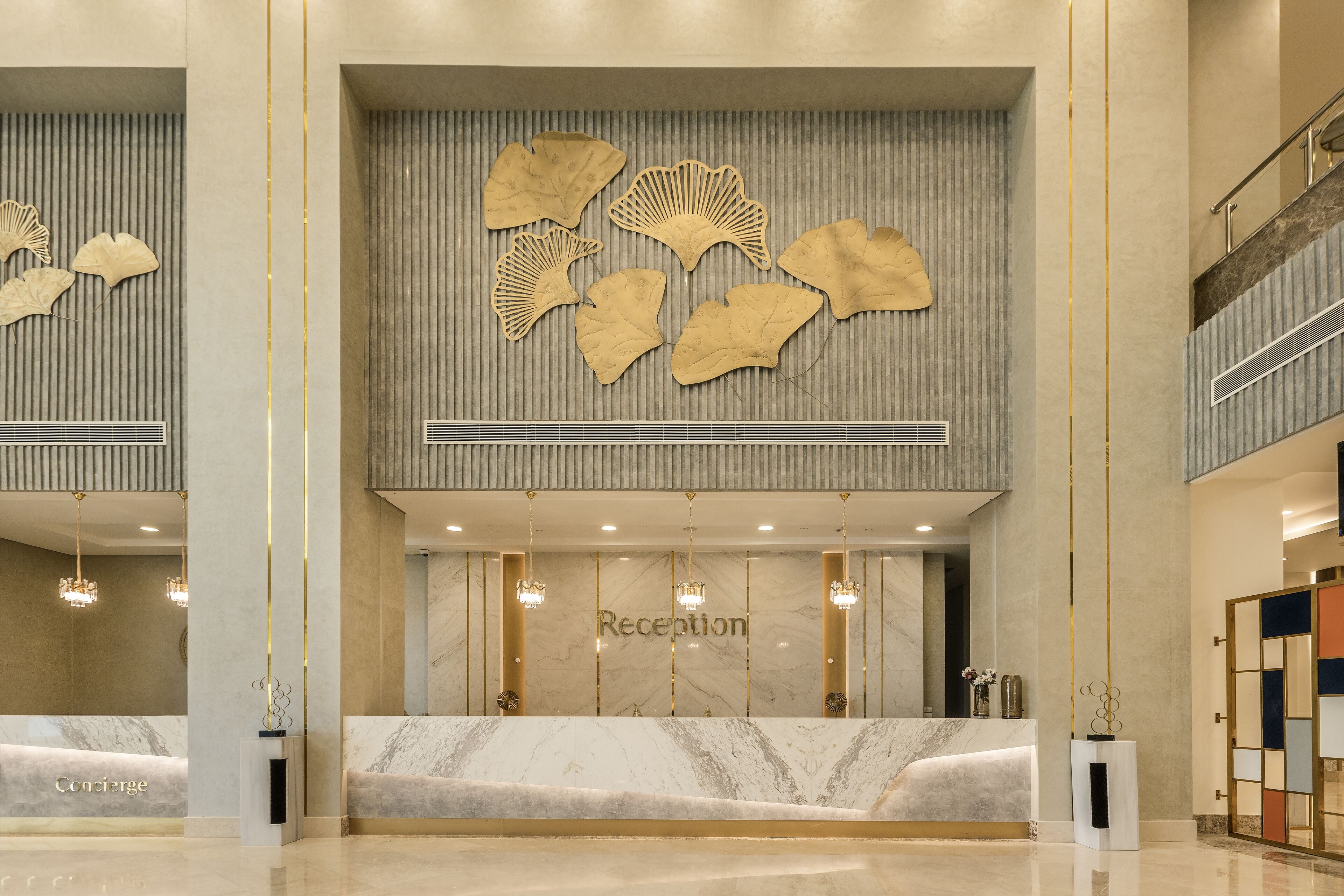 A reception area with a marble counter, a wall with decorative leaf patterns, and a staircase.
