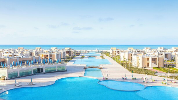 A resort with multiple swimming pools, a bridge, and a view of the ocean. - Gewan Resort New Alamein (Marsa Matrouh)
