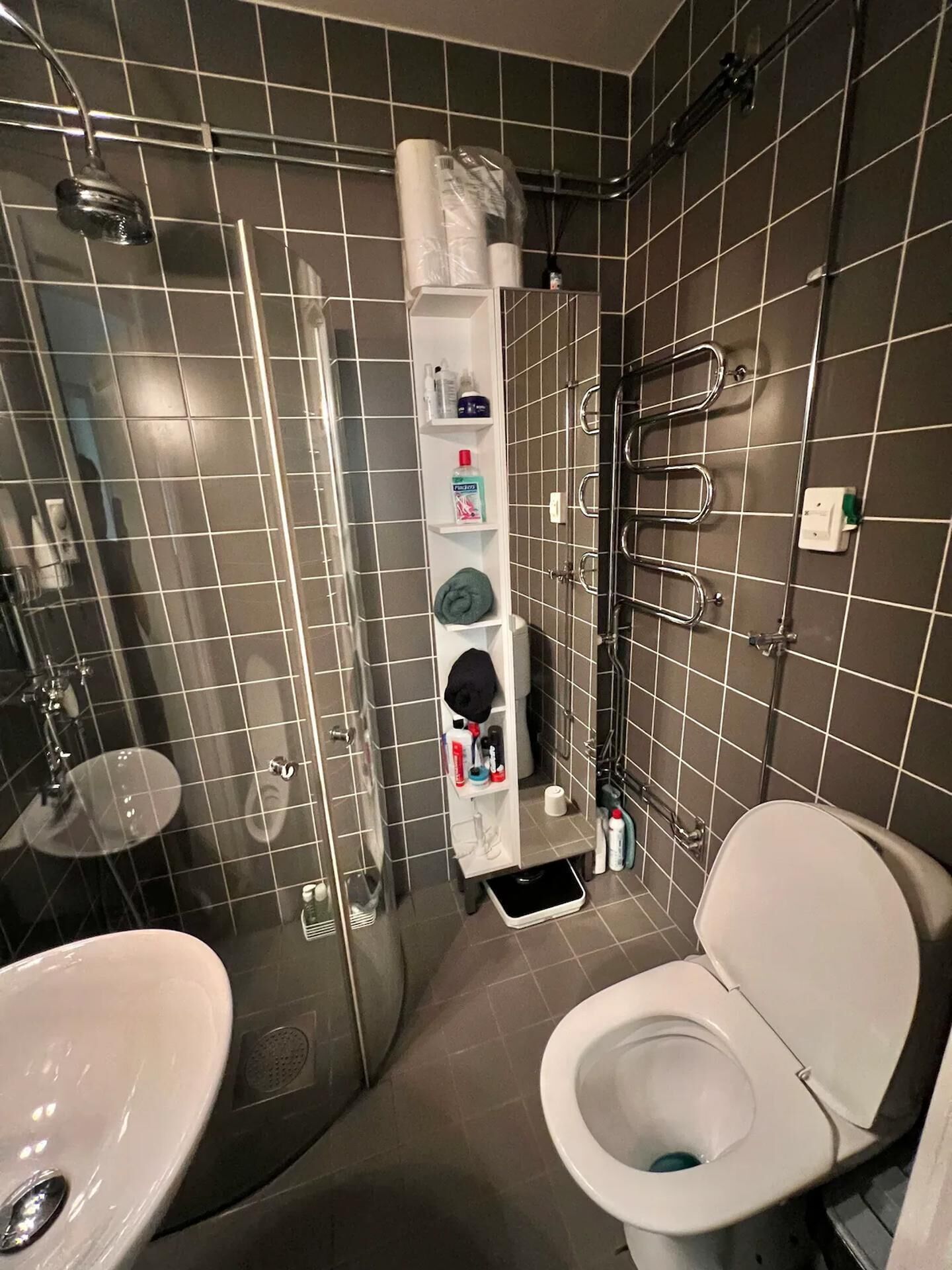 A compact bathroom with a toilet, sink, and shower.