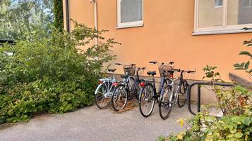 A row of bicycles parked against a building with a window and a door.