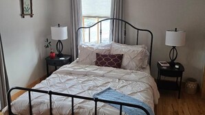 A single bed with a metal frame, two bedside tables with lamps, a window with curtains, and a picture on the wall. - Located in beautiful/historic downtown Peninsula in the heart of a National Park (Peninsula)
