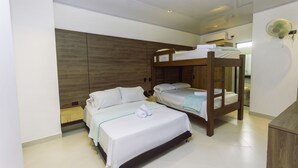 Un dormitorio con literas, cabecera de madera, mesita de noche y ventilador de pared.