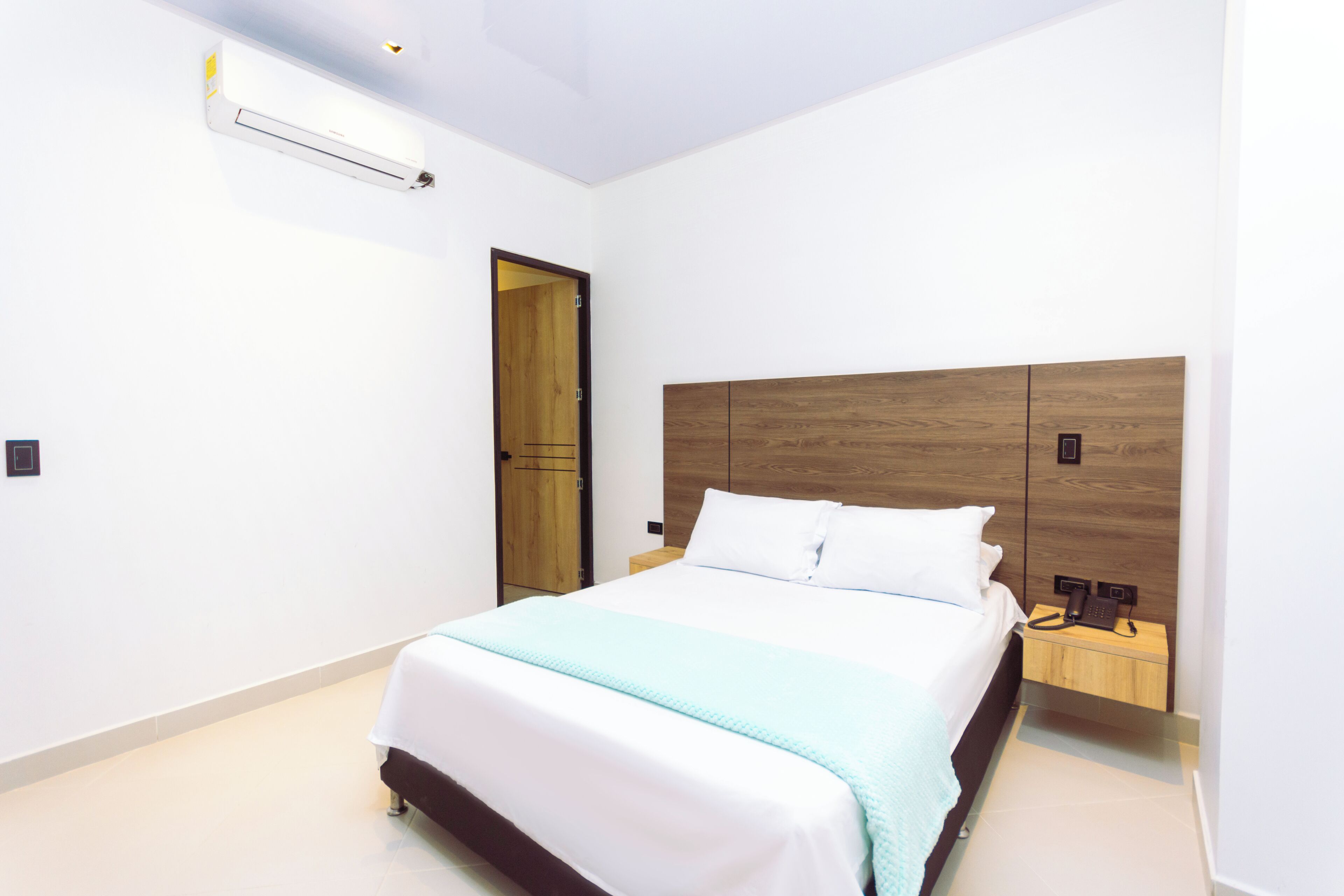 A bedroom with a bed, bedside table, and a wooden headboard.