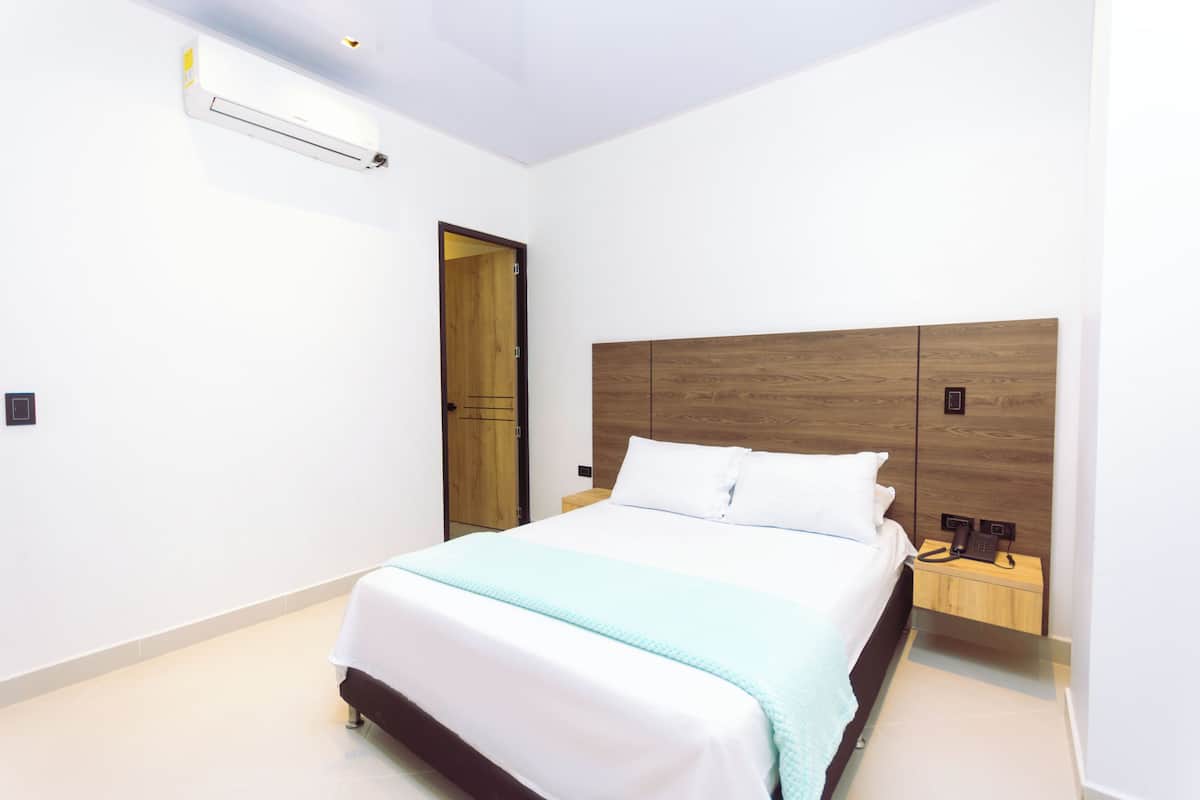 A bedroom with a bed, bedside table, and a wooden headboard.