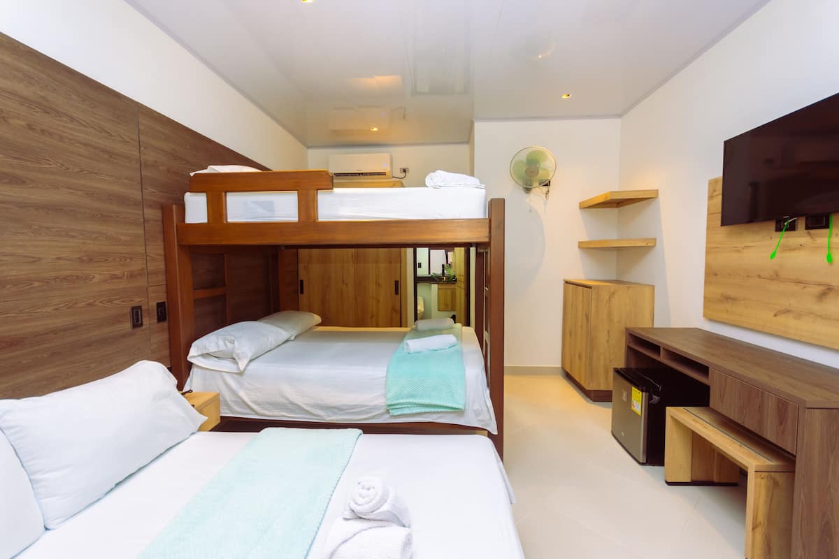 A hotel room with bunk beds, a TV, a fan, and wooden furniture.
