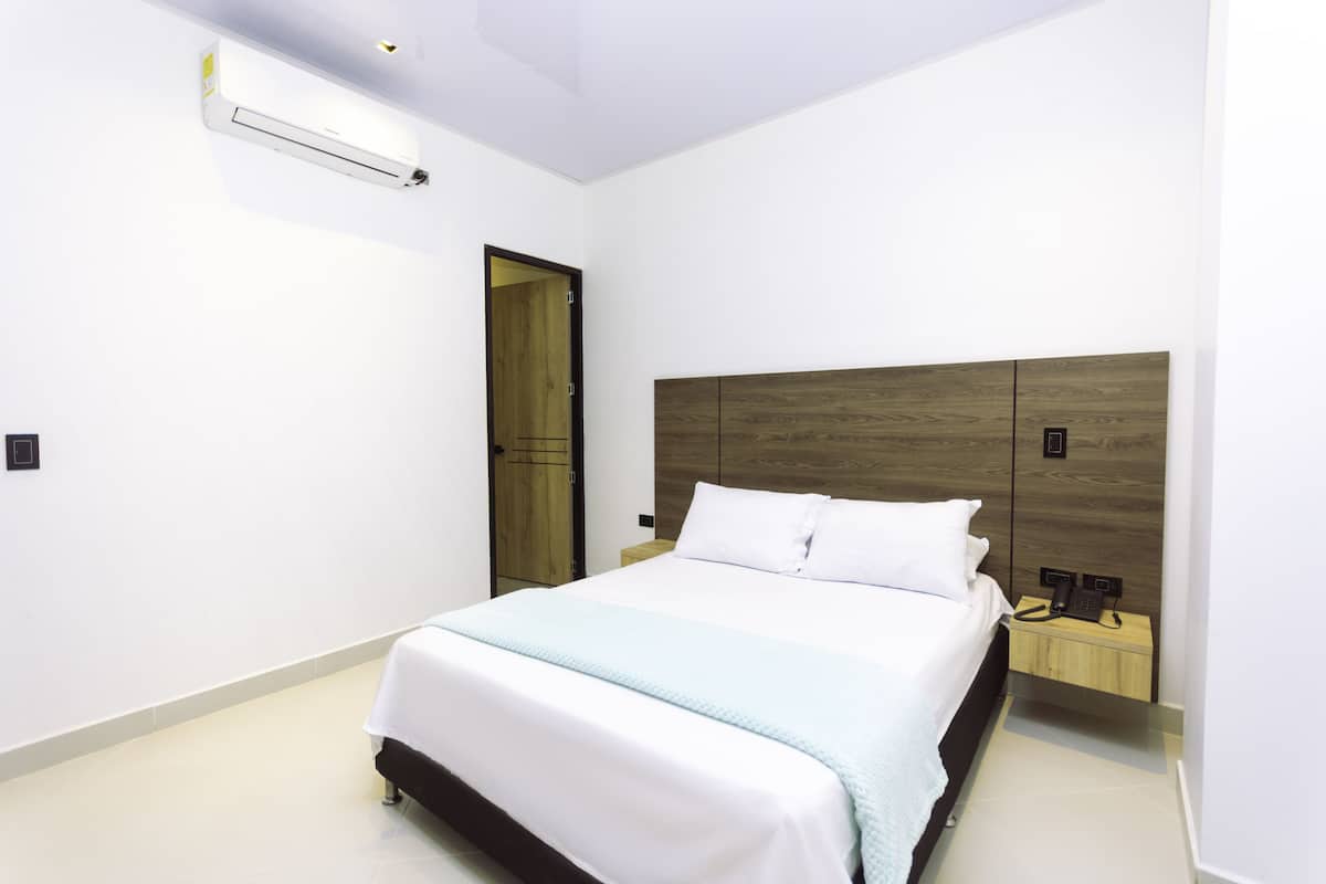 A bedroom with a bed, bedside table, and a wooden headboard.
