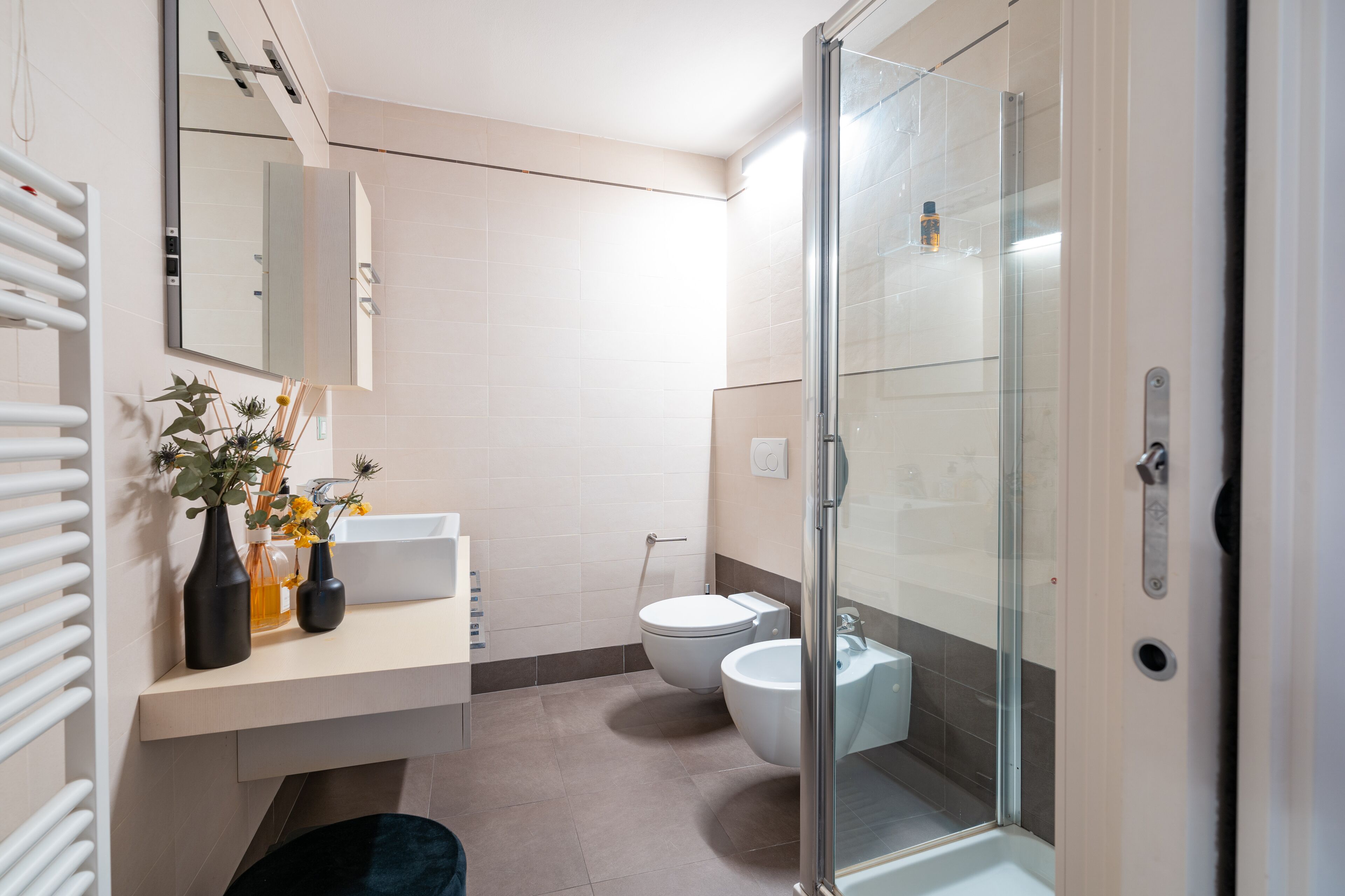 Ein modernes Badezimmer mit einer Glaskabine zur Dusche, einem weißen Waschbecken und einer Toilette.