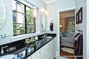 A modern bathroom with a large mirror, black countertop, and a glass shower enclosure. - The Home Collection - Hermitage Court (Charlotte)