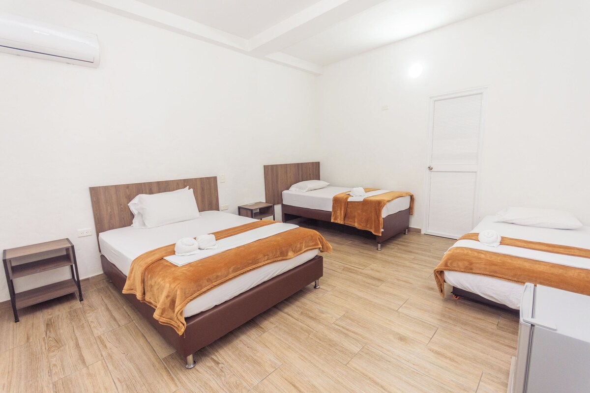 A hotel room with two beds, a small bedside table, a wardrobe, and a white door.