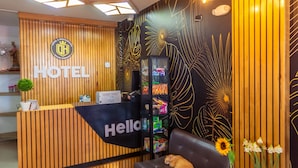A hotel reception area with a wooden reception desk, a sofa, and a cat.