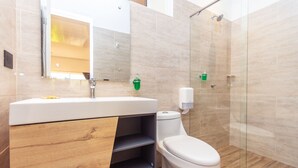 A modern bathroom with a wooden vanity, a toilet, a glass shower enclosure, and a mirror.