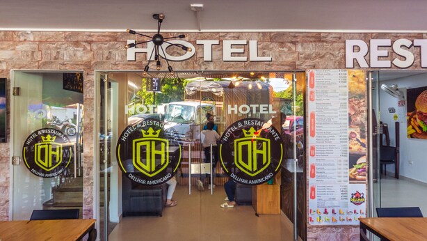 A hotel entrance with a wooden ceiling, a reception desk, and a visible menu board.
