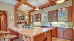 A spacious kitchen with wooden cabinets, a large island with stools, and pendant lighting. - Luxe & Stylish Santa Fe Home Rental Near Downtown! (Santa Fe)