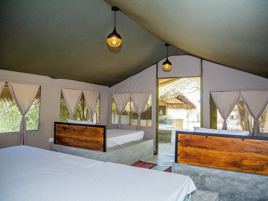 A tented accommodation with two beds, each with wooden headboards, and a view of the surrounding landscape.