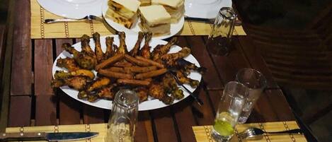 A dining table set for a meal with plates of food, including grilled chicken, sandwiches, and a salad.